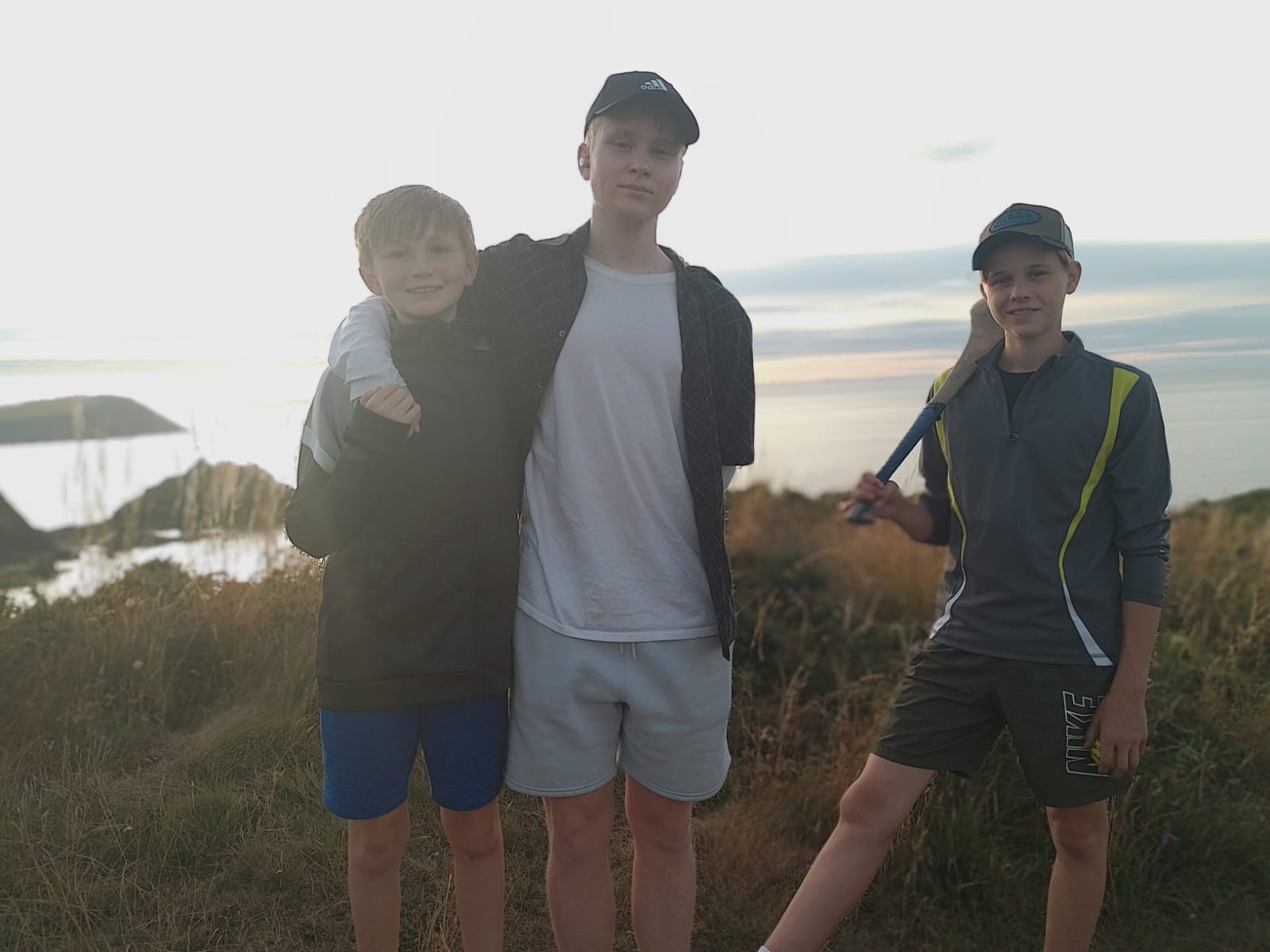 Melissa’s three sons smiling on a clifftop walk in Newport, Wales at sunset