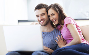 Couple-Sitting-On-Couch-Searching-For-Home-Insurance
