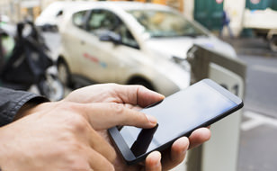 Person Holding Smartphone That Records Their Car's Activity Via Telematics