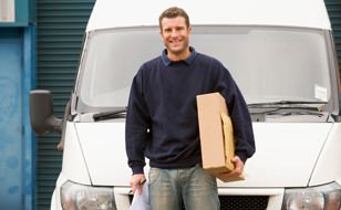 Van driver holding a box stood in front of van