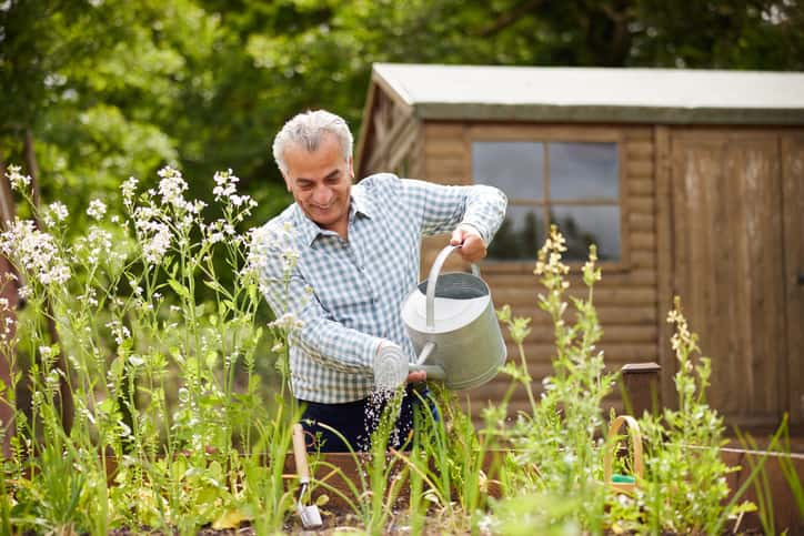 man watering flowers in his garden