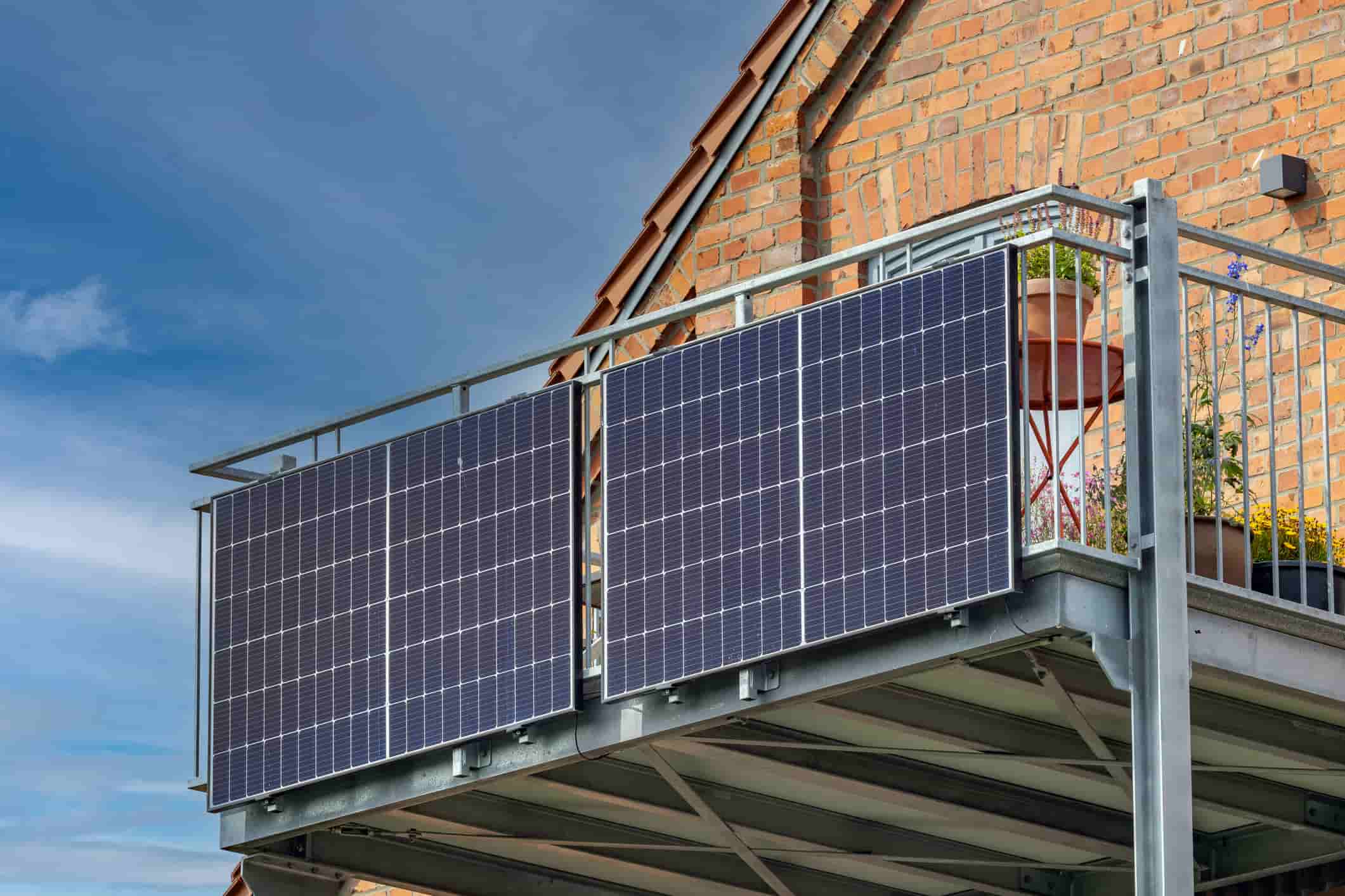 Two solar panels mounted on a steel balcony railing against a brick building, an example of plug-in balcony solar.