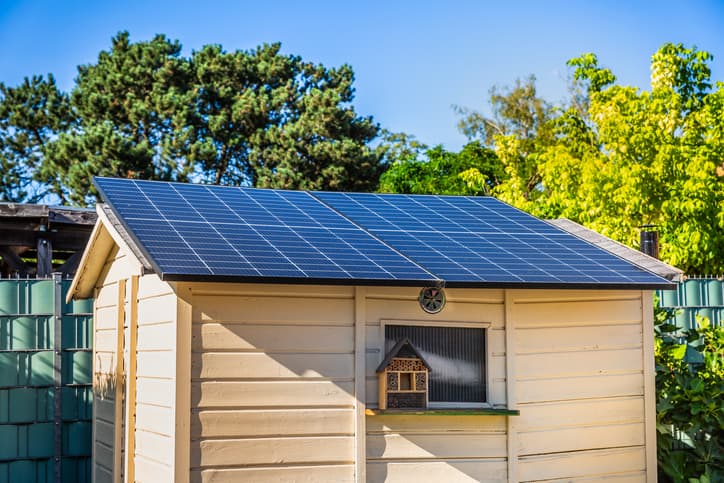 Solar panels mounted on the roof of a garden shed surrounded by trees
